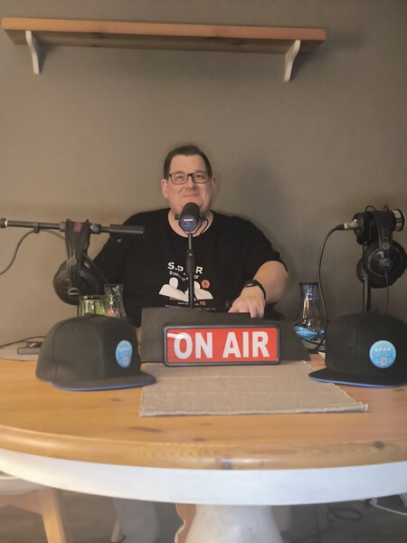 Sascha sitzt am Mikrofon im SPÄR-Setup und richtet die Technik für die Aufnahme mit Ina Hoinkis ein.